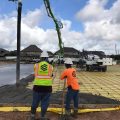 Two workers survey a concrete job site with Cribbs Concrete safety vests and safety helmets on.