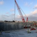 A crane stands above a concrete job site at sunrise.